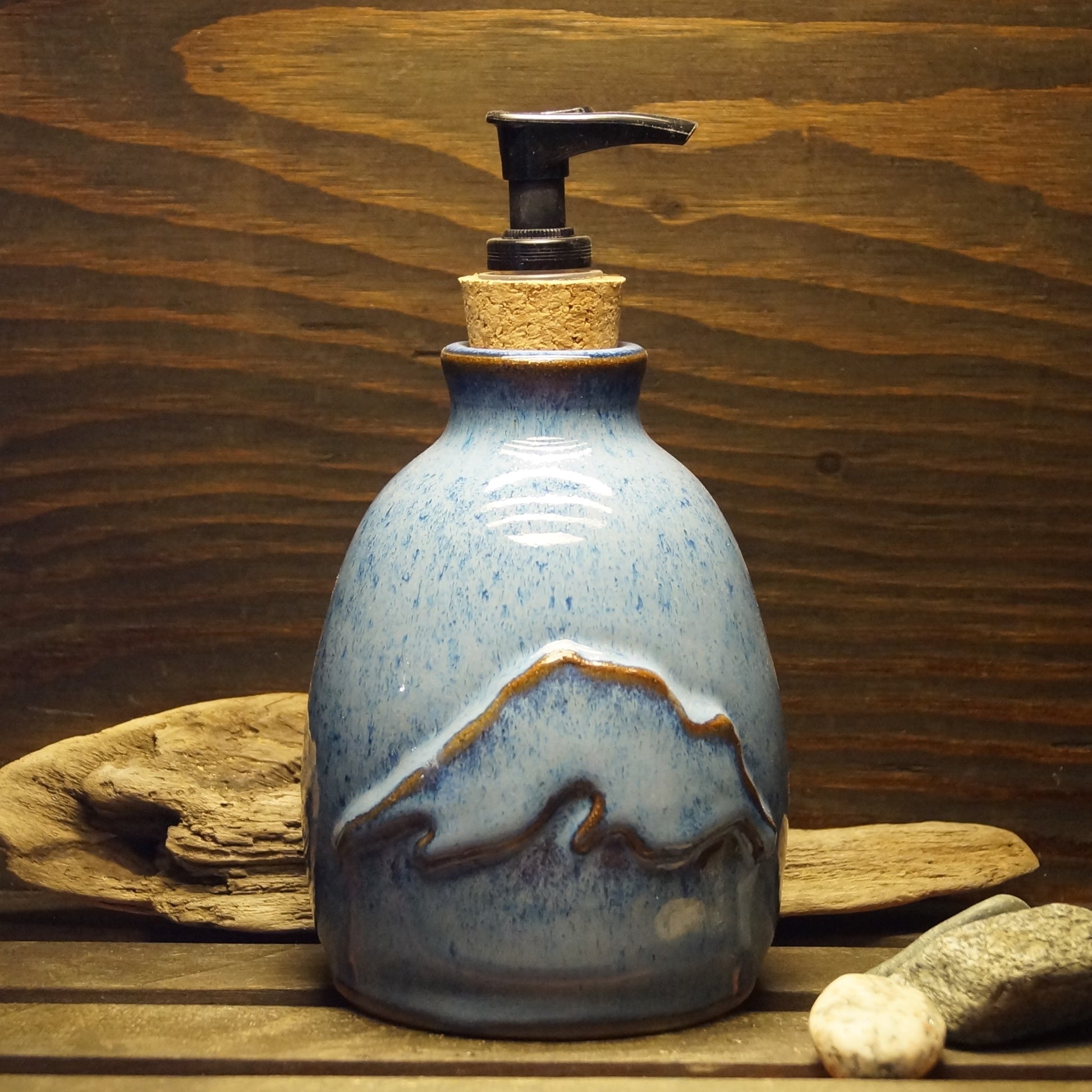 A blue and brown hand made pottery soap dispenser with a Lake Superior design.