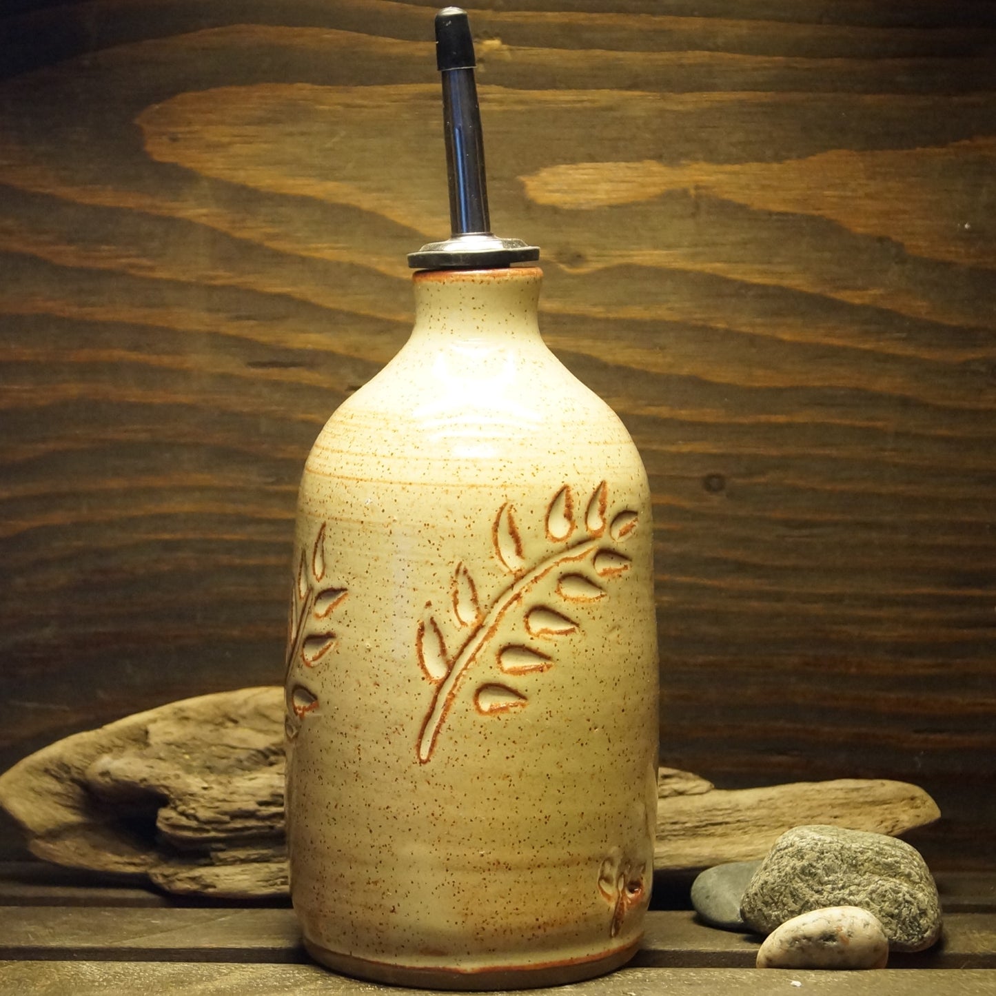 A white hand made pottery oil bottle with a botanical design.