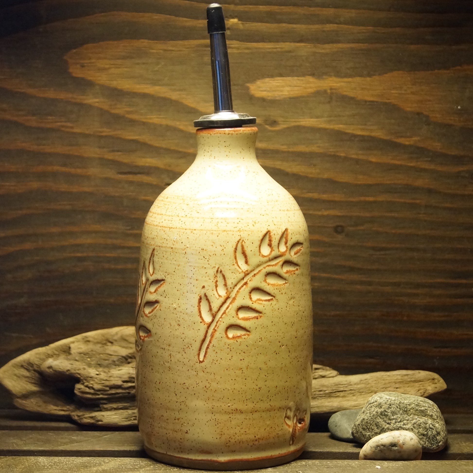 A white hand made pottery oil bottle with a botanical design.