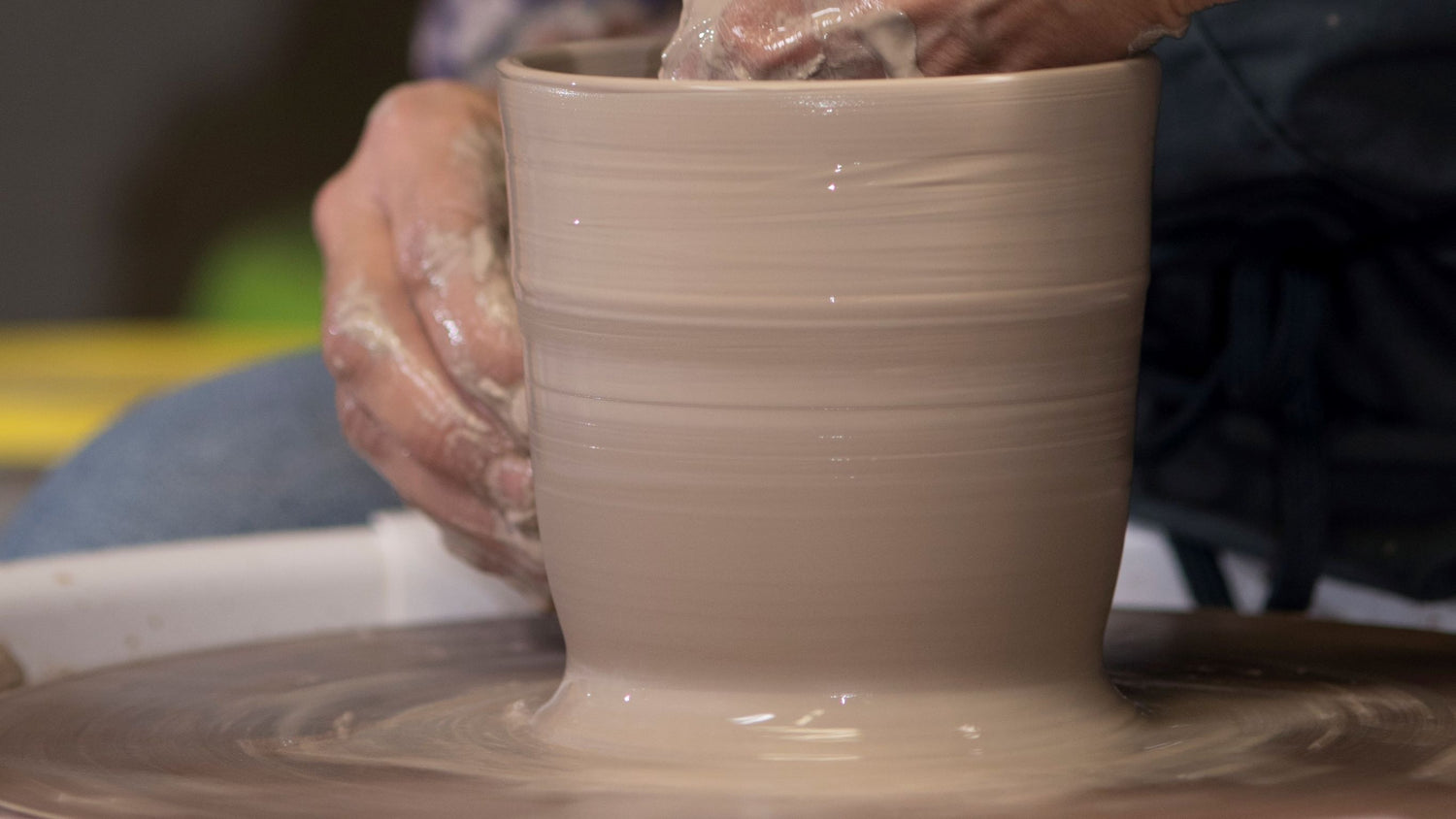 A zoomed in photo of Cindy hand throwing clay into a hand made pottery gift.