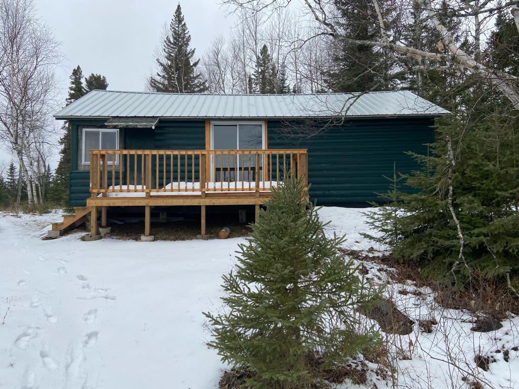 A green cabin near Lake Superior that was the inspiration for Cindy, the founder of Green Cabin Pottery. She would often see this cabin as a child, and purchased it as an adult after naming her company. It is winter in this photo and snow is on the ground.