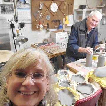 Cindy, the maker and founder of Green Cabin Pottery and her father who helps her make pottery at their pottery throwing studio in Wawa, Ontario. They are smiling looking at the camera.